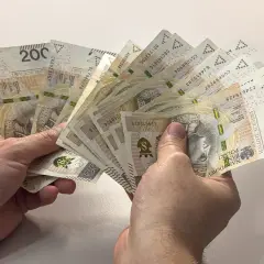 Dwie ręce trzymają wachlarz banknotów po 200 złotych. Czy to duł, czy dół, ważne, że pieniądze są!