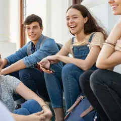Uśmiechnięci przyjaciele siedzą razem, dzieląc się śmiechem i być może pytaniami do przyjaciółki.