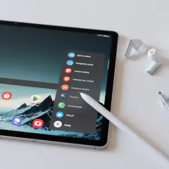 Tablet z rysikiem, słuchawkami i długopisami. Menu tabletu oferuje opcje takie jak "Tłumacz" czy "Sklep Play", co ułatwia kupowanie i kupywanie wirtualnych dóbr.