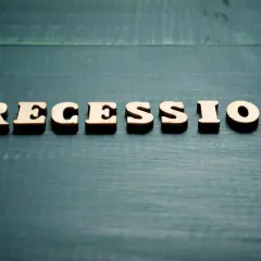 Drewniane litery układają słowo "RECESSION". To pojęcie ekonomiczne, które oznacza spadek aktywności gospodarczej.