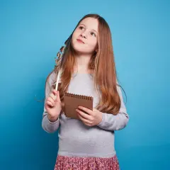 Dziewczynka z piórkiem w dłoni, zastanawia się nad słowami. Czyżby tworzyła aliterację?