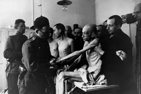 Wstrząsający obraz ofiar obozu koncentracyjnego, ukazujący skrajne wycieńczenie. To wizualna definicja holocaustu.