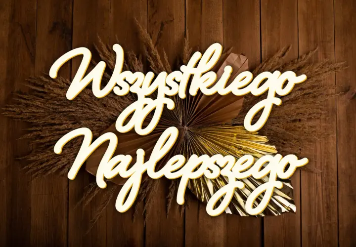 Napis "Wszystkiego najlepszego" ozdobiony suszonymi trawami i złotym wachlarzem na drewnianym tle.