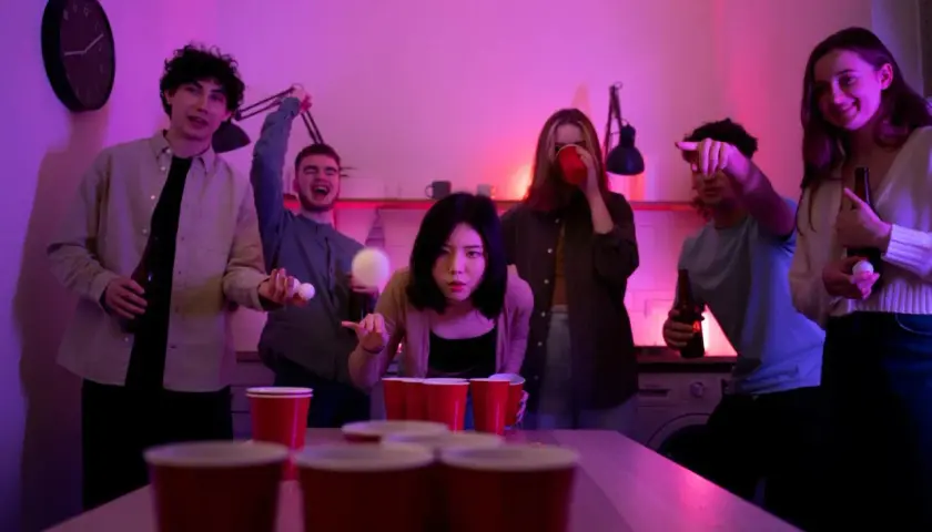 Młodzi ludzie grają w beer ponga, a atmosfera jest pełna śmiechu i zabawy. To idealny moment na pytania do nigdy przenigdy.