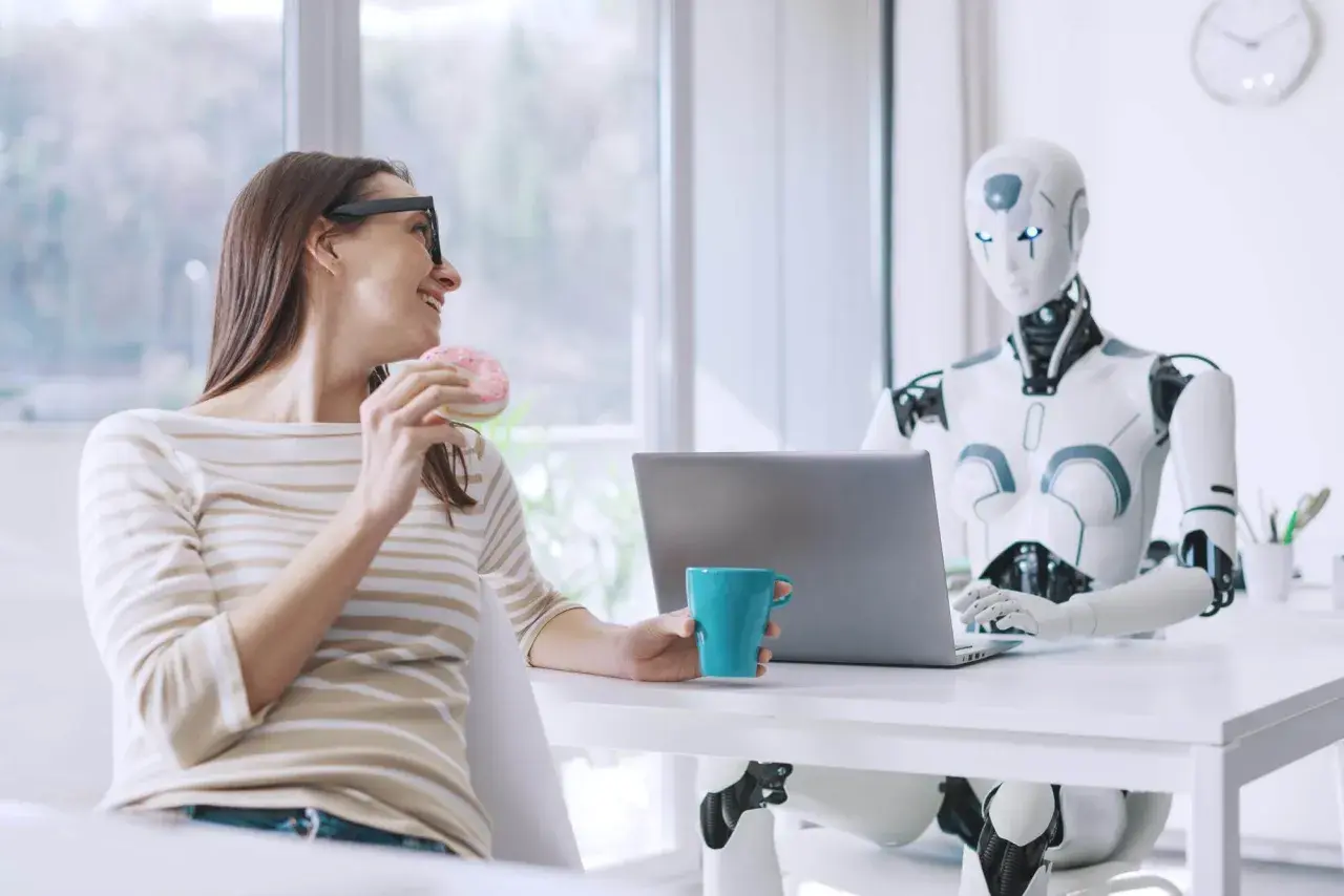 Kobieta z pączkiem i kubkiem kawy rozmawia z robotem przy laptopie. Oryginalna scena z przyszłości.