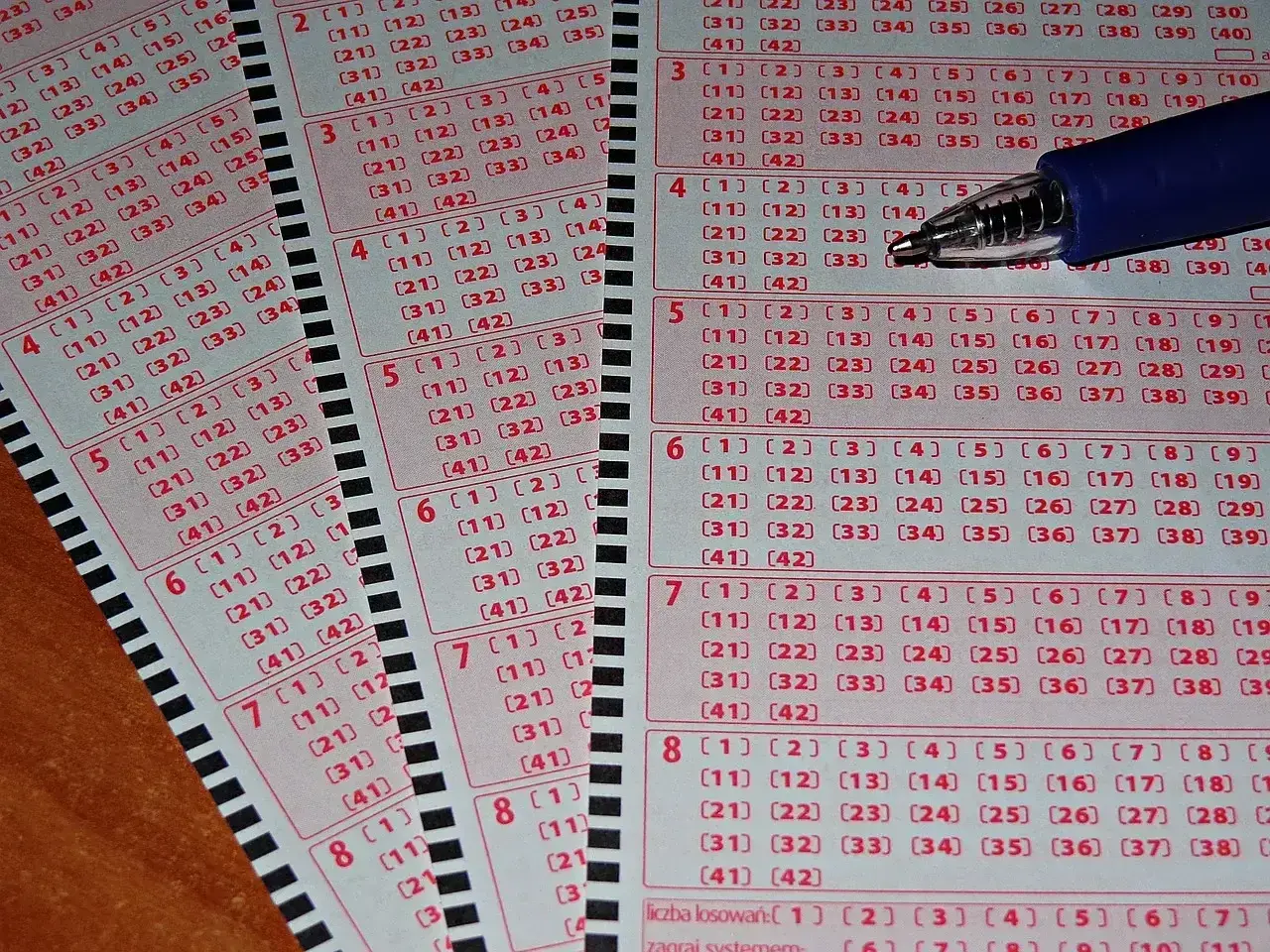 Kupony lotto z zaznaczonymi polami, gotowe do gry. Widoczne litery kontrolne zdrapek i numerowane pola do wyboru liczb.