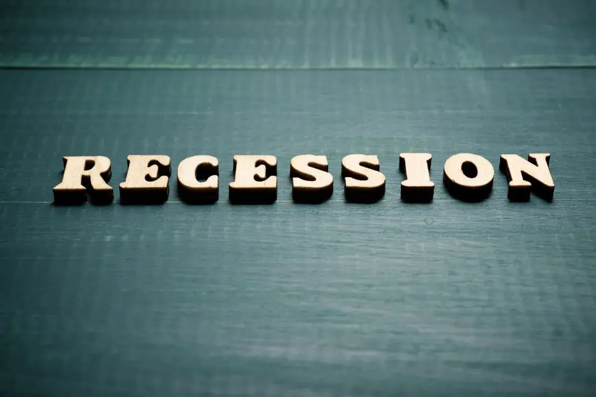 Drewniane litery układają słowo "RECESSION". To pojęcie ekonomiczne, które oznacza spadek aktywności gospodarczej.
