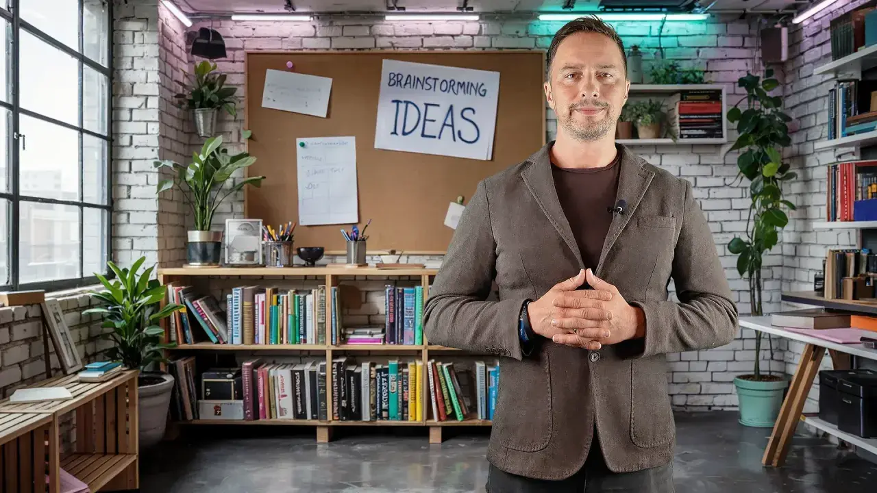 Mężczyzna w marynarce stoi przed tablicą z napisem "BRAINSTORMING IDEAS". W związku z tym, otoczenie sugeruje kreatywne środowisko pracy.