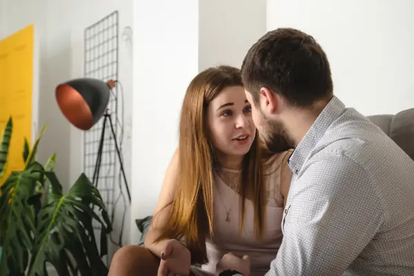 Para rozmawia, nawiązując głęboki kontakt wzrokowy. Mężczyzna w koszuli patrzy na kobietę, która gestykuluje.